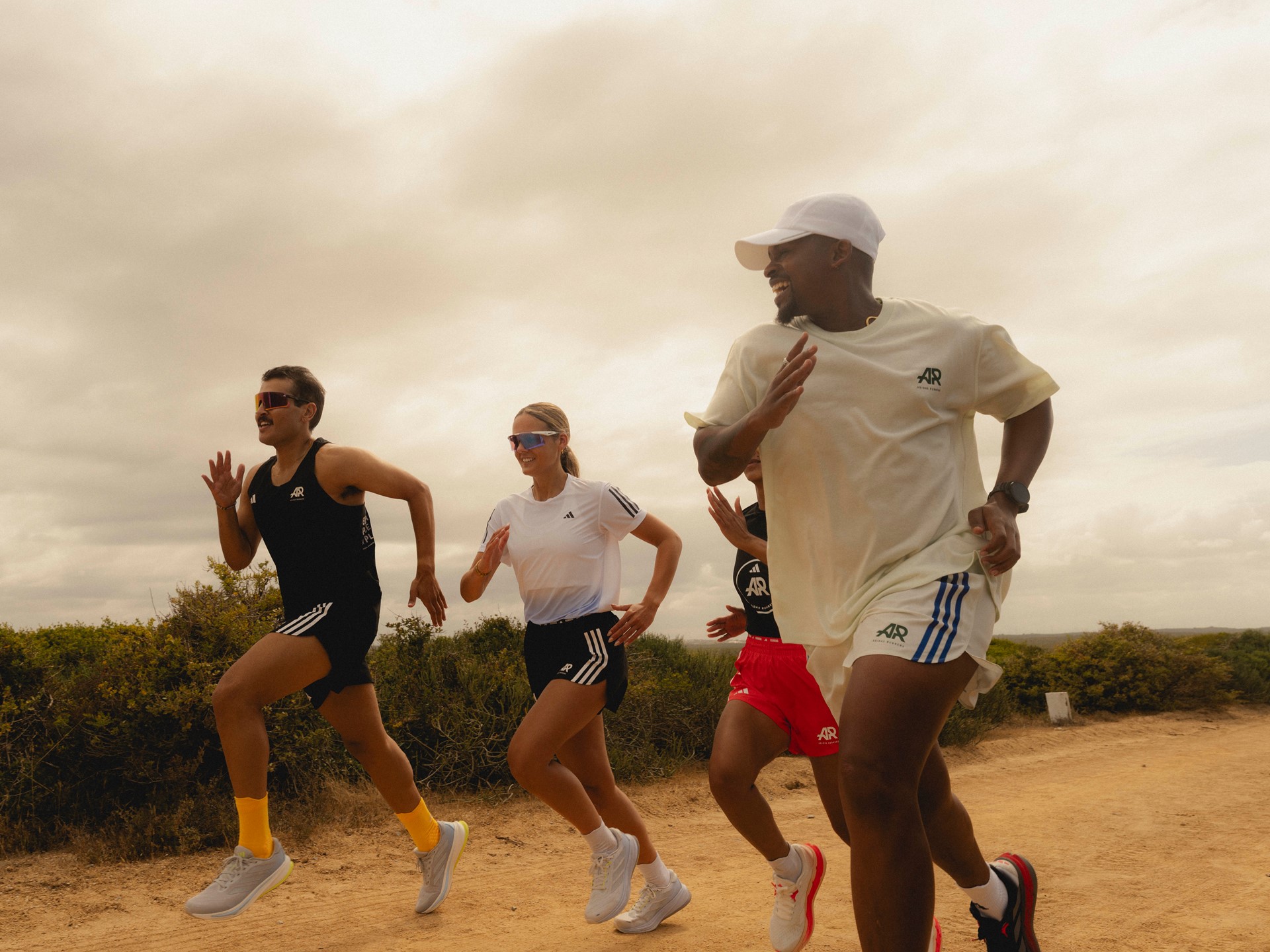 Grupo de atletas adidas corriendo juntos por un sendero al aire libre