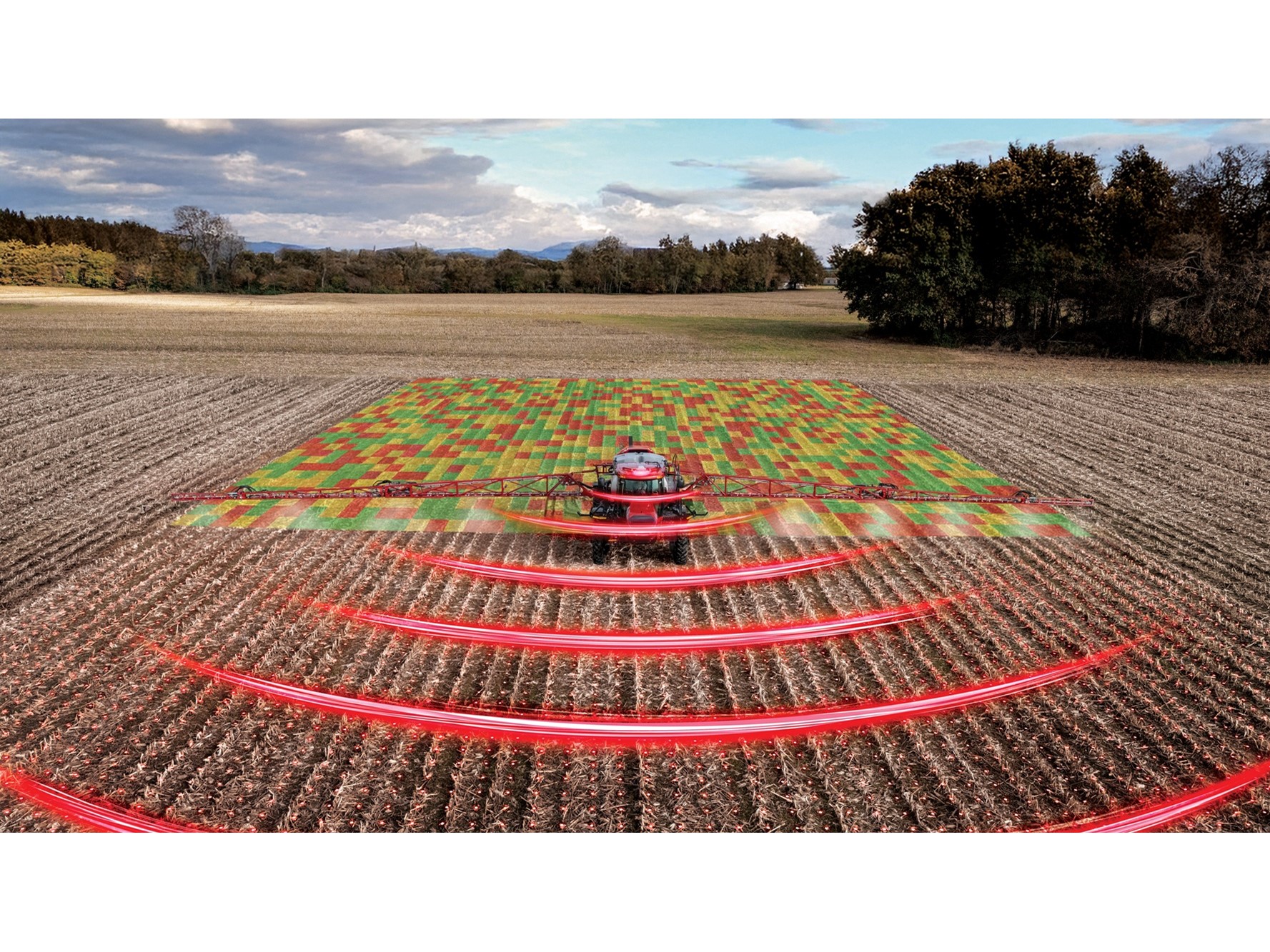 A red agricultural tractor equipped with advanced technology is spraying a field, with a digital overlay showing a colorful grid pattern on the crops and red curved lines representing sensor or radar signals, illustrating precision farming and smart agriculture techniques in a rural landscape under a partly cloudy sky.