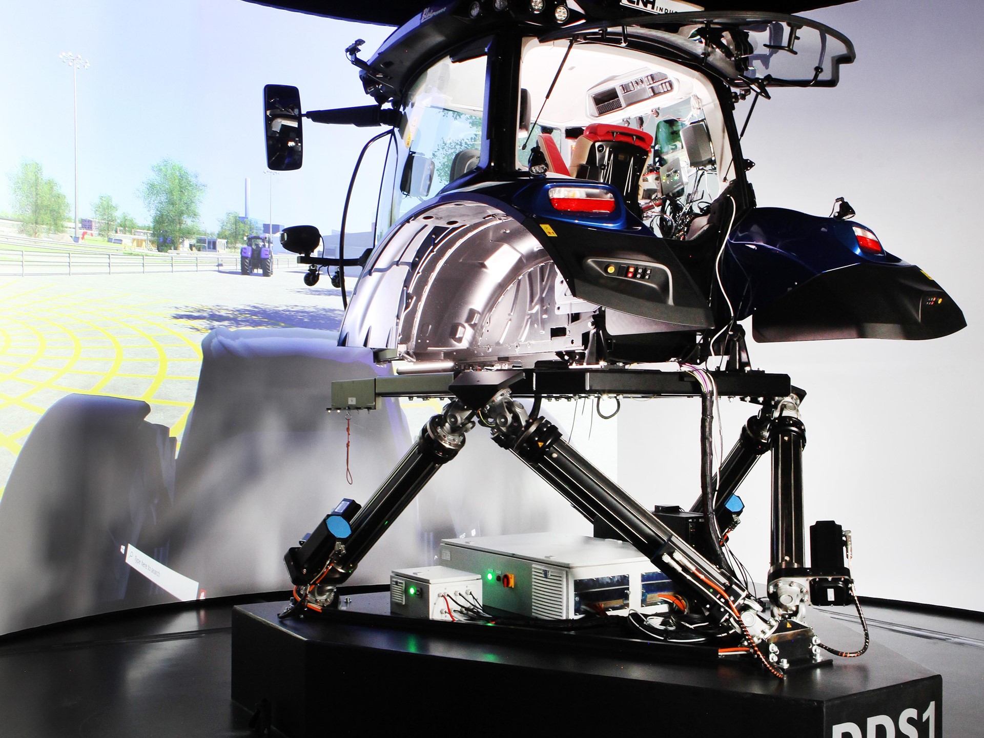 A high-tech driving simulator setup featuring a tractor cabin mounted on a multi-axis motion platform labeled "DDS1," with a large curved screen in the background displaying a virtual outdoor environment, designed for immersive agricultural machinery training or testing.