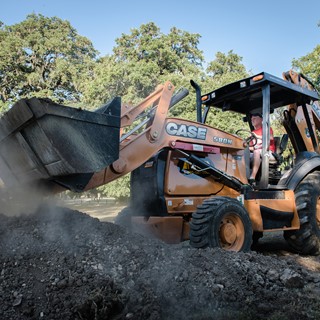 CASE 580N moving aggregate during construction of the San Marcos skate park in Texas
