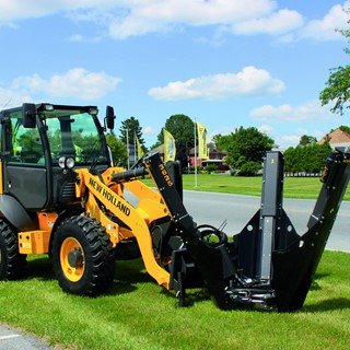 New Holland Construction with a tree removal implement attached