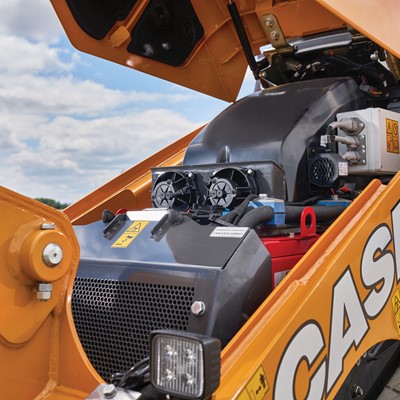 Close up view of the open engine compartment of a yellow CASE TL100EV electric mini track loader under a partly cloudy sky
