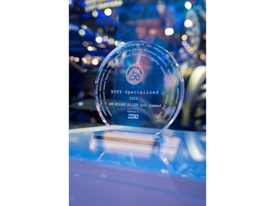A clear circular glass award trophy with the inscription "TOTY Specialized 2026 NEW HOLLAND T4.120F Auto Command" and the logo "Tractor of the Year" featuring a tractor icon. The award is sponsored by BKT and is displayed on a reflective surface with a blurred background of blue and purple lights.