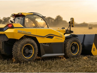 A yellow New Holland TH hybrid power agricultural loader with large rugged tires is parked on a harvested field during sunset, showcasing its modern design and front bucket attachment.