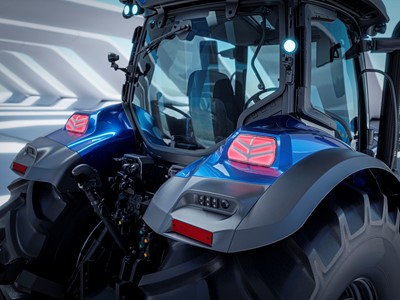 Close-up view of the rear section of a modern blue tractor with large black tires, illuminated rear lights, and a glass-enclosed cabin, set against a futuristic, well-lit background.