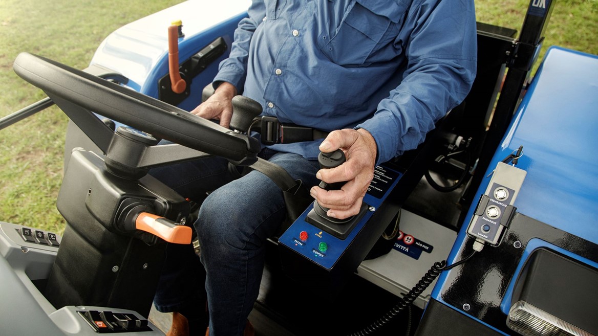The farmer shows how to use the control stick to drive the tractor
