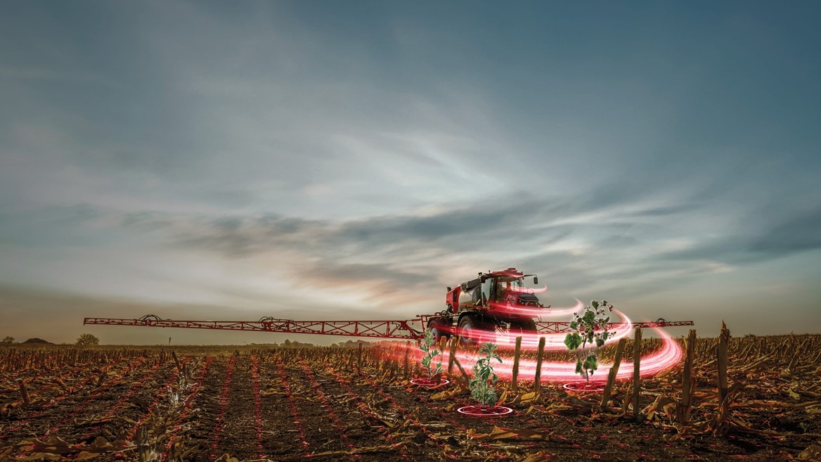 A modern agricultural sprayer is operating in a field at dusk, with a dramatic sky in the background. The sprayer is surrounded by swirling red light effects, emphasizing its motion as it applies treatment to the crops. The field is lined with rows of plants, showcasing a blend of technology and farming practices.
