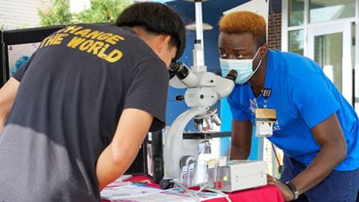 Adeyinka Akinsanya chats with the teenager standing opposite him and explaining slides he’d slipped under a microscope..