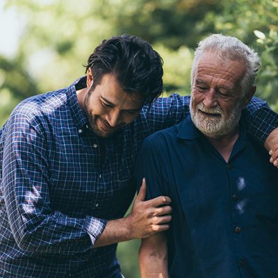 Young man with arm over shoulder of older man outdoors