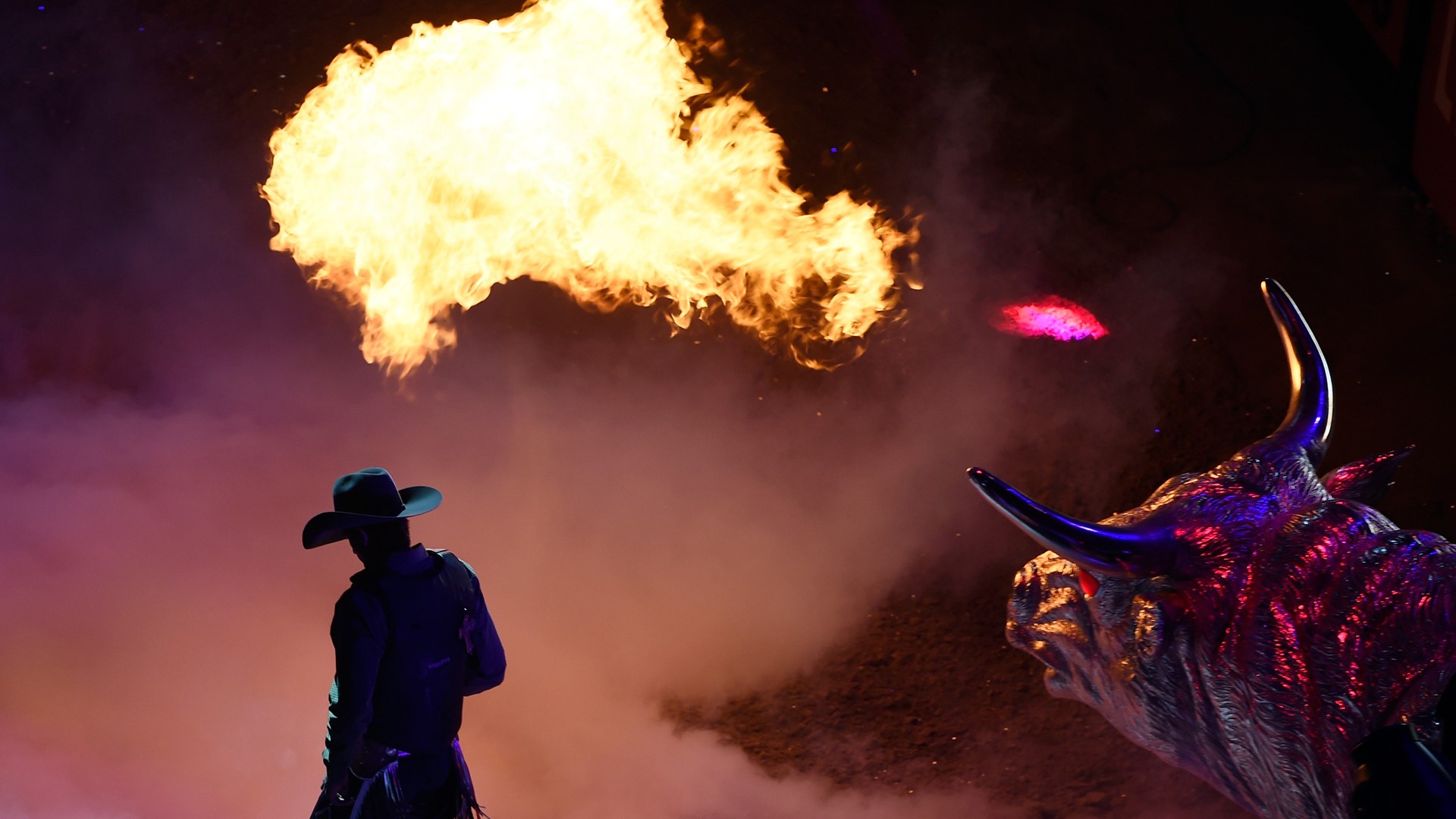 A bull rider introduced with a fire breathing bull statue