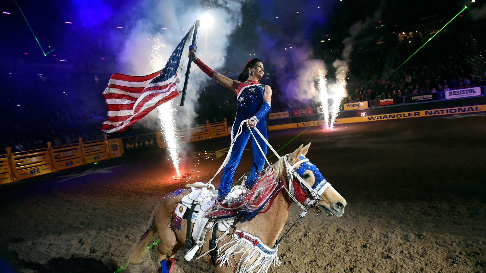 A rider carries the American flag during the opening ceremonies at the start of the seventh go-round of the NFR