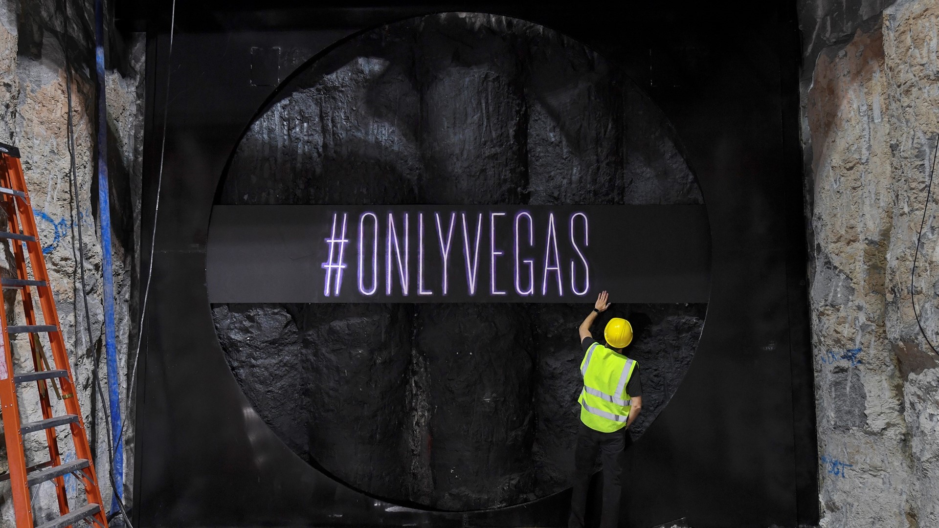 Ryan Rabbass works on painting the LVCVA’s new slogan “#onlyvegas” on the wall of a pit that The Boring Company drill
