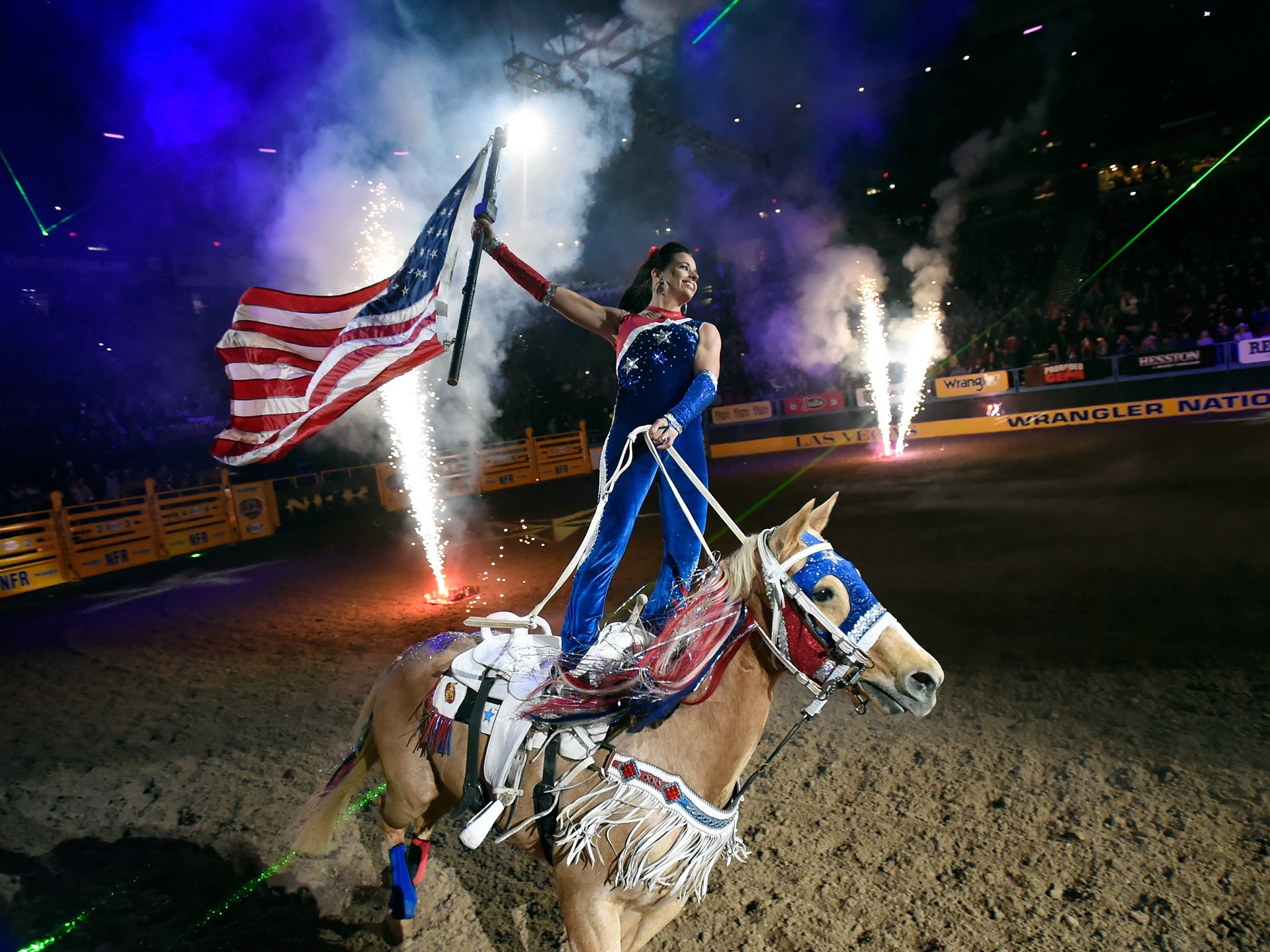 A rider carries the American flag during the opening ceremonies at the start of the seventh go-round of the NFR