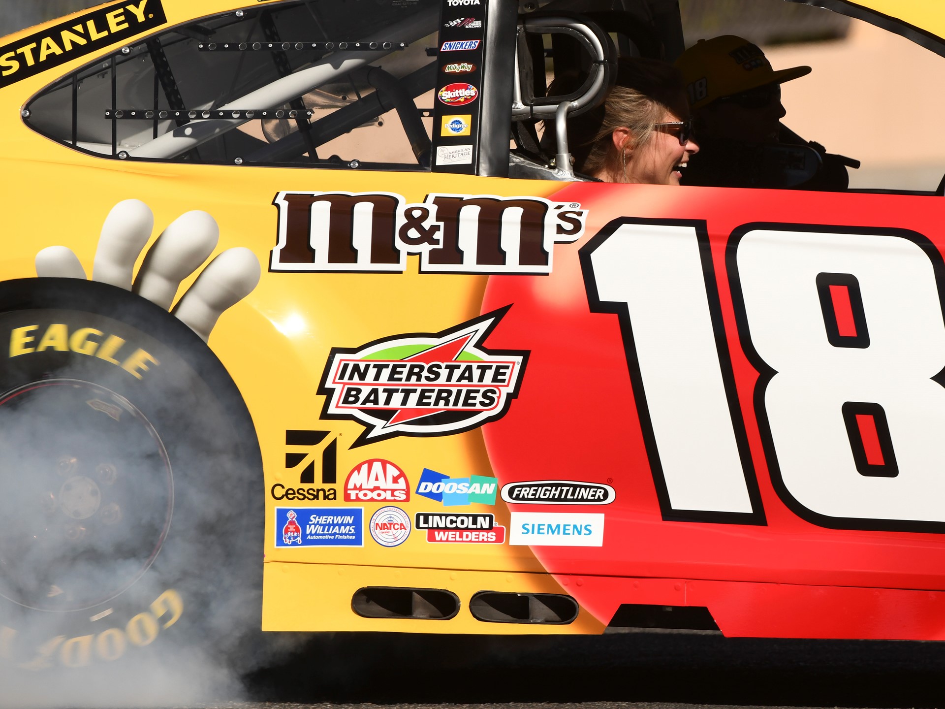 A passenger laughs while riding in Kyle Busch's car during the 2018 NASCAR Burnout Blvd
