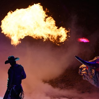 A bull rider introduced with a fire breathing bull statue