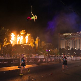 Runners pass under an aerialist as the Mirage volcano erupts during the Rock 'n' Roll Las Vegas Marathon