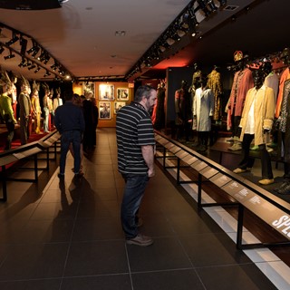 Guests look at a collection of stage outfits at the Rolling Stones "Exhibitionism"