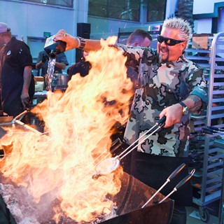 Guy Fieri pours tequila on a charcoal fire