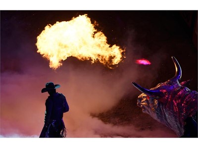A bull rider introduced with a fire breathing bull statue