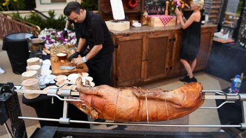 A pig roasts on a spit at the Buddy V's booth