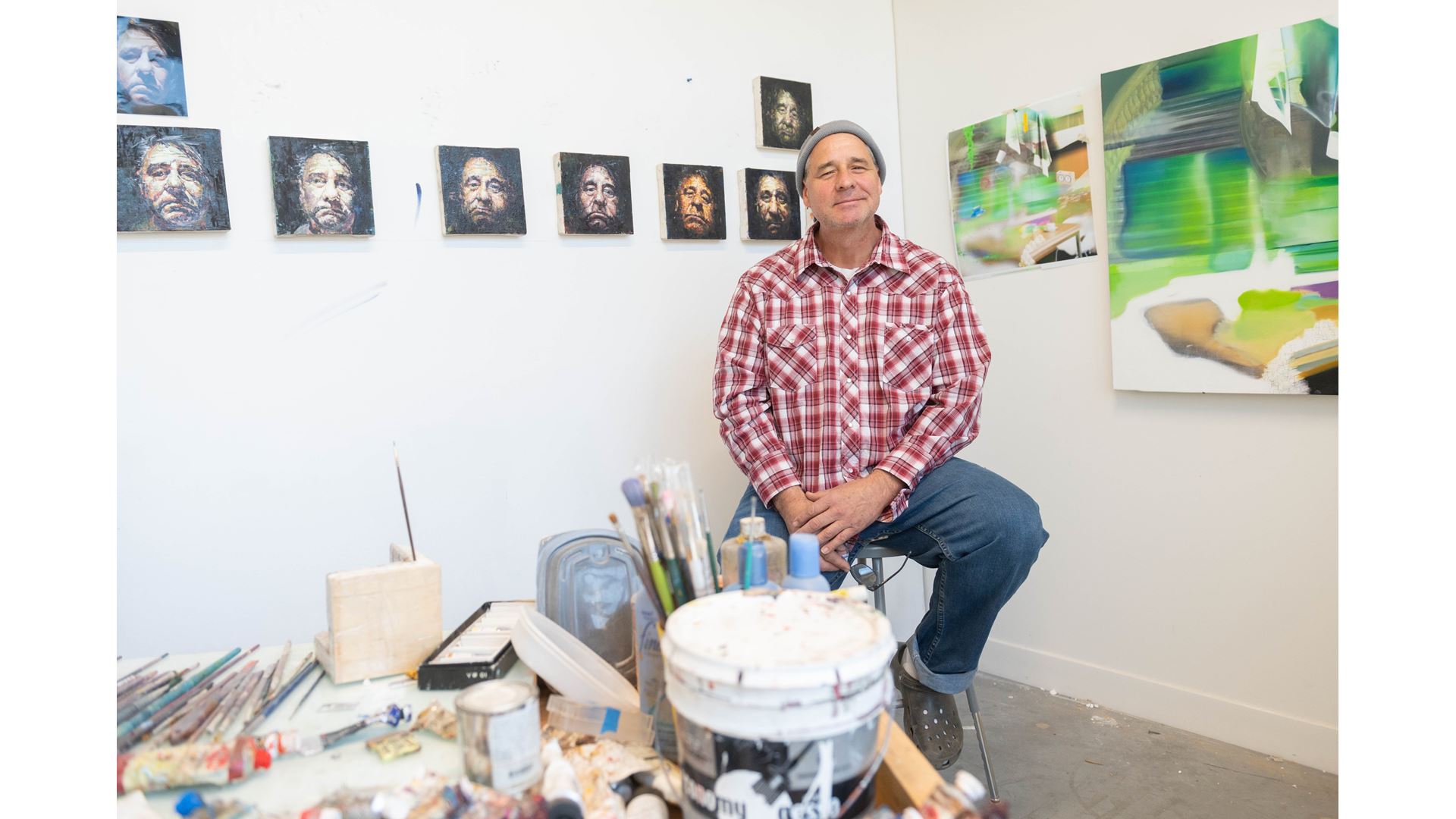 A man sitting in front of small paintings