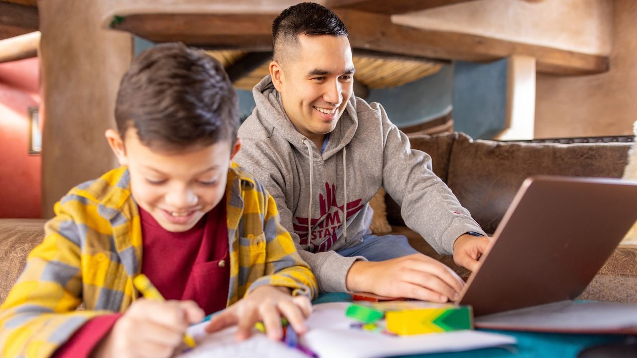 IMAGE DESCRIPTION A man using a laptop while seated next to a boy