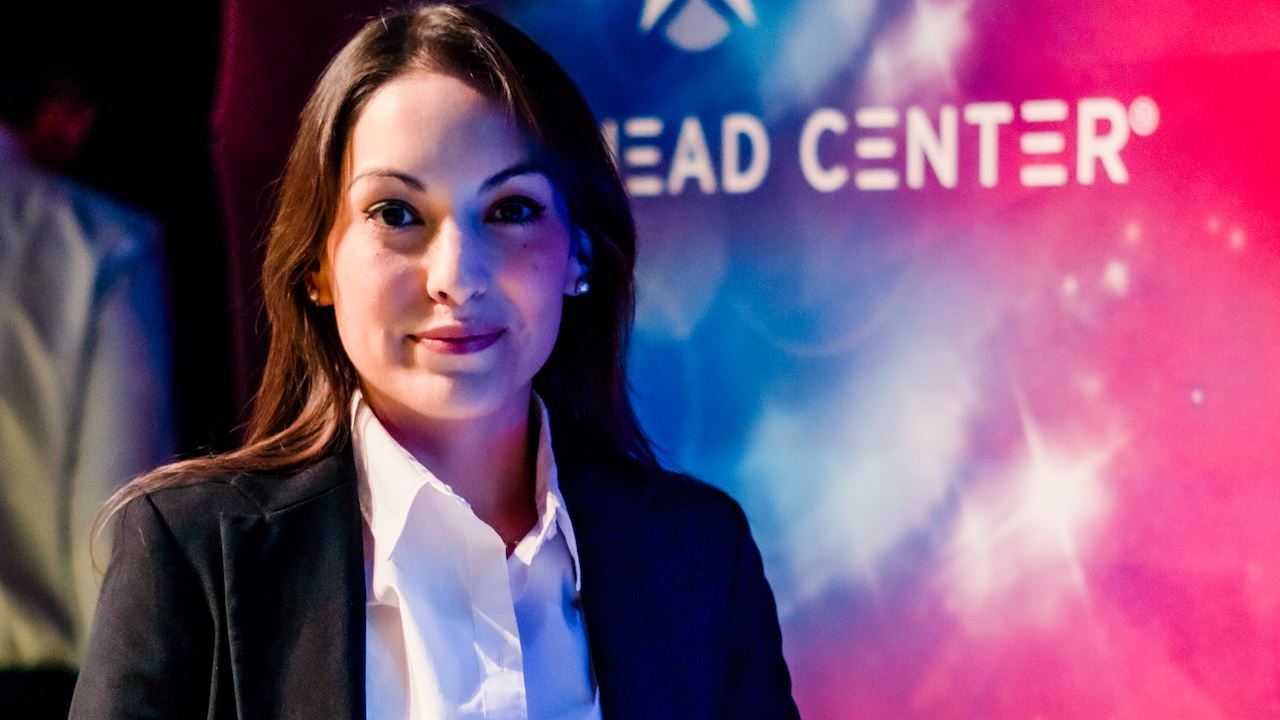 Head and shoulders of a woman standing next to a table with awards