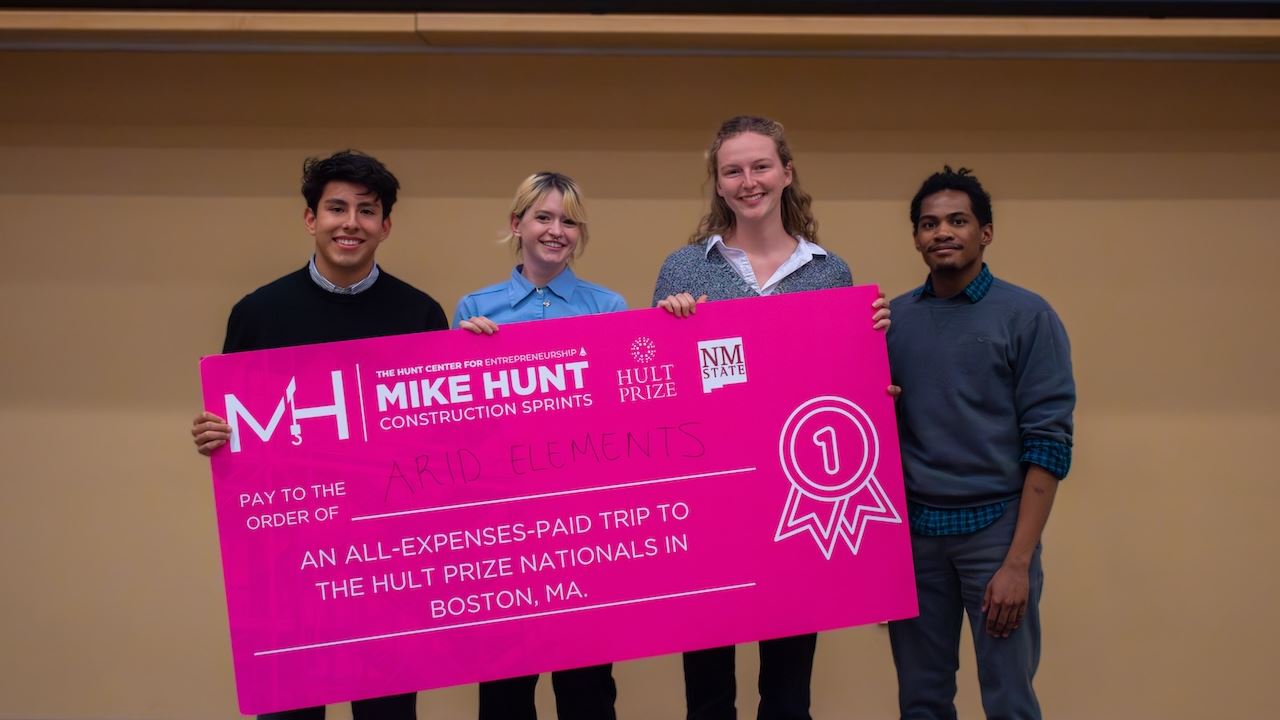 Four people holding an oversized check