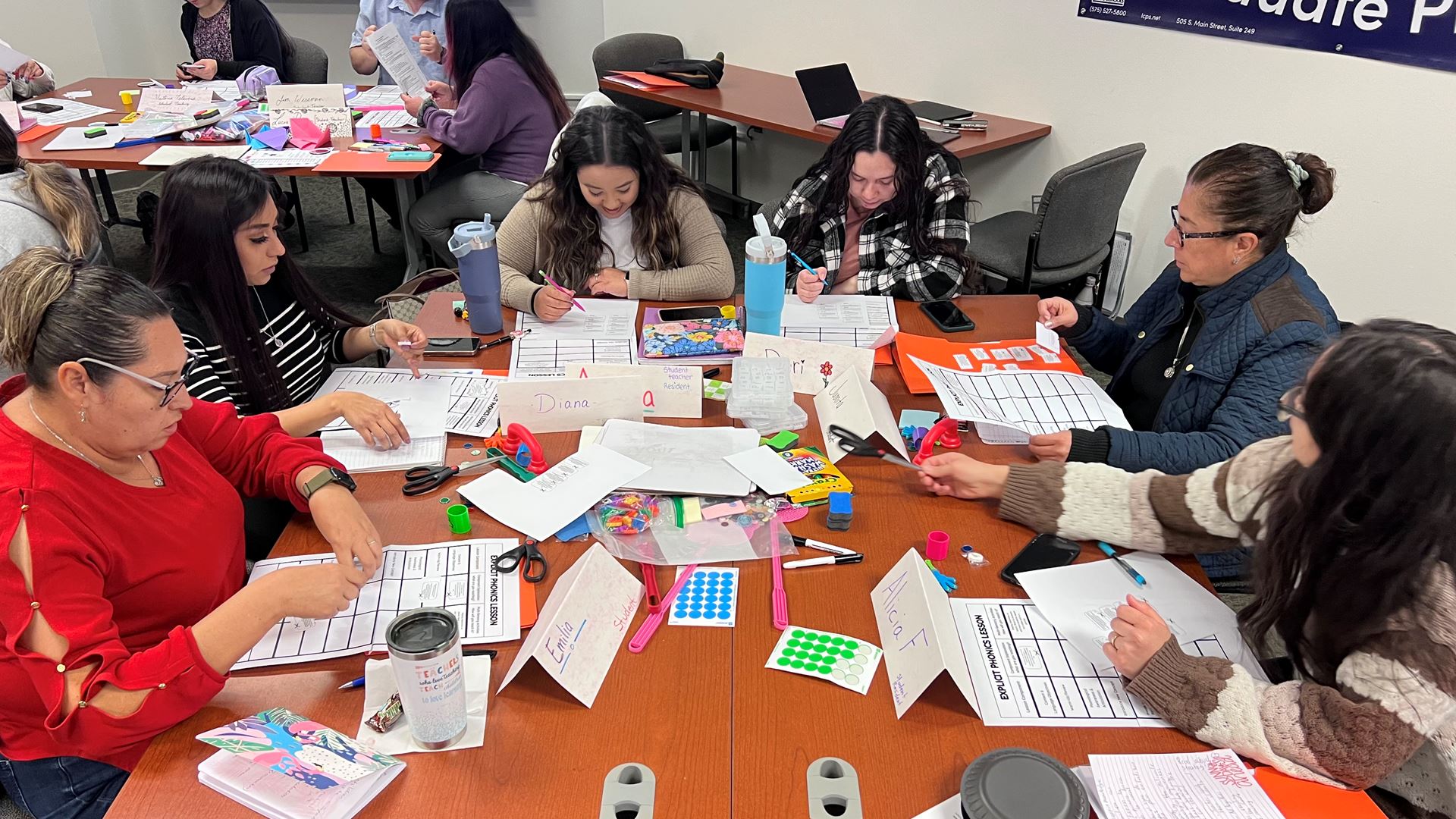 IMAGE DESCRIPTION A group of women seated at a table with various stationary supplies