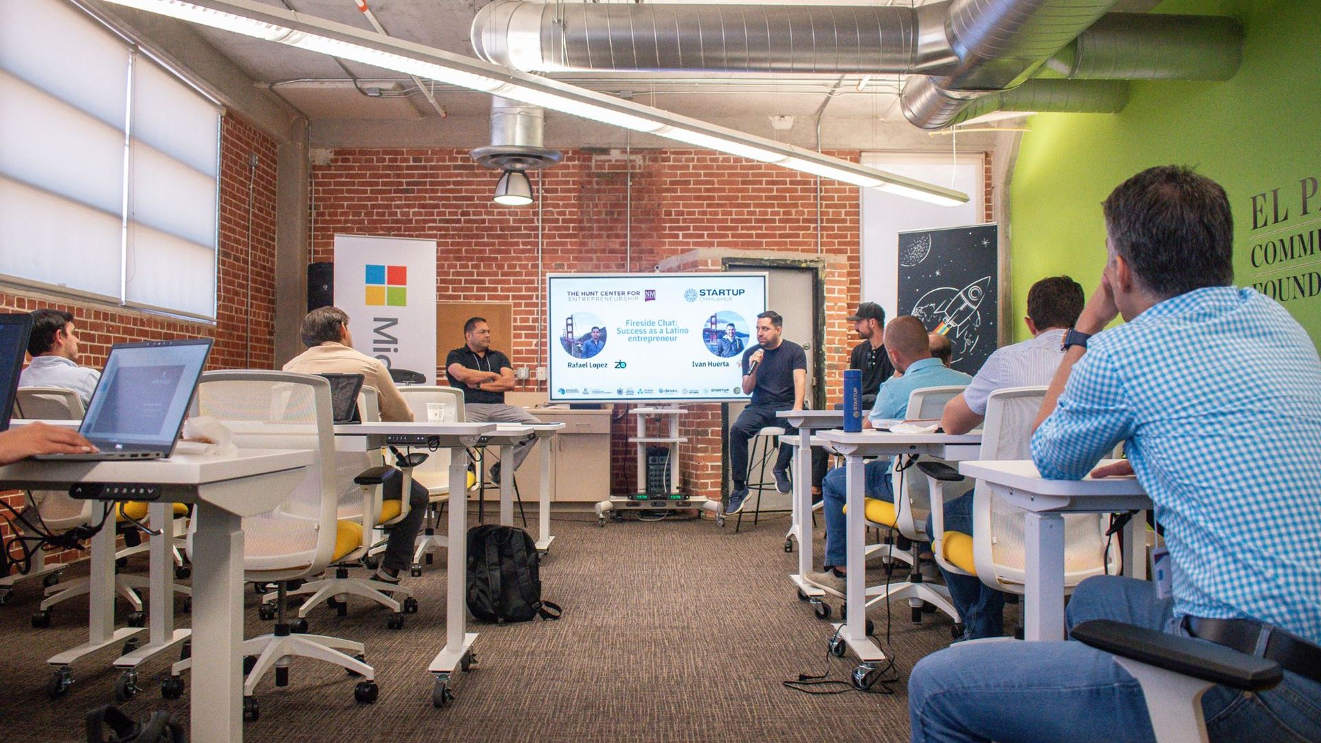 IMAGE DESCRIPTION Three men presenting in front of a group of people in a room