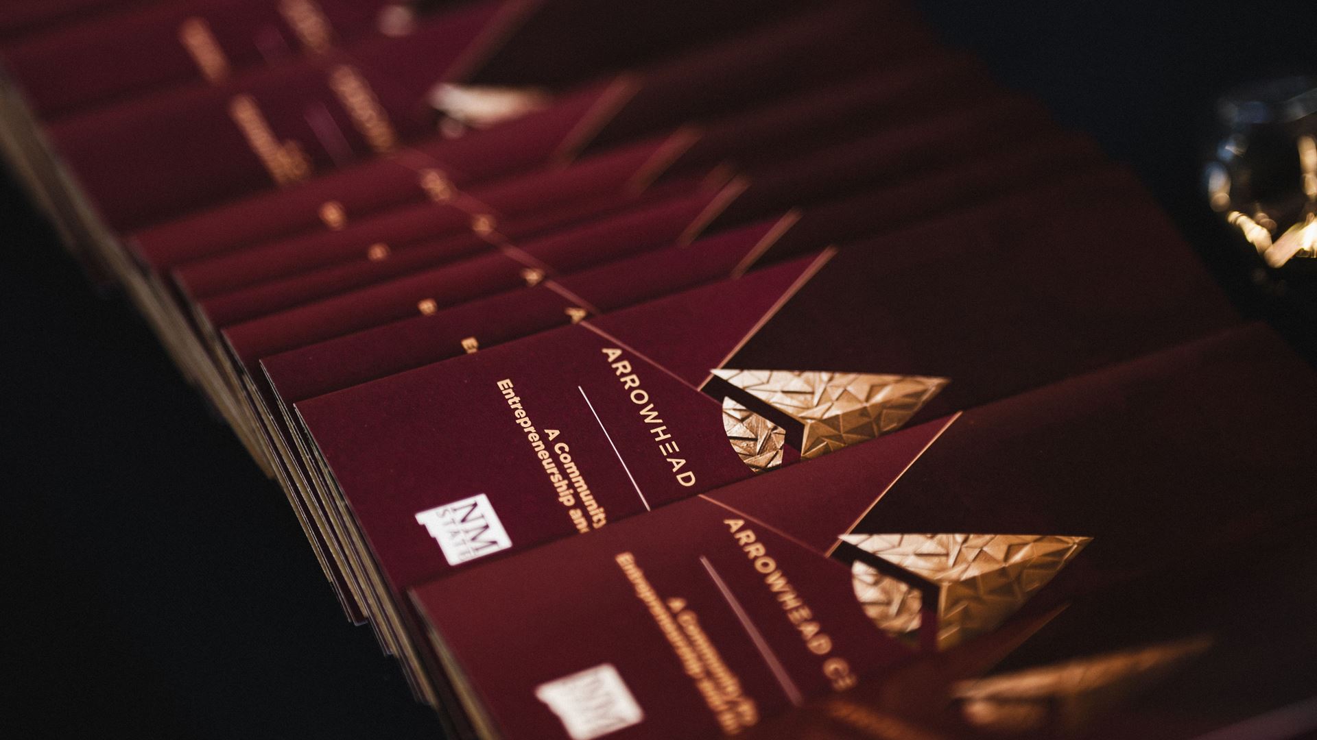 IMAGE DESCRIPTION A row of programs with gold foil lettering on a table