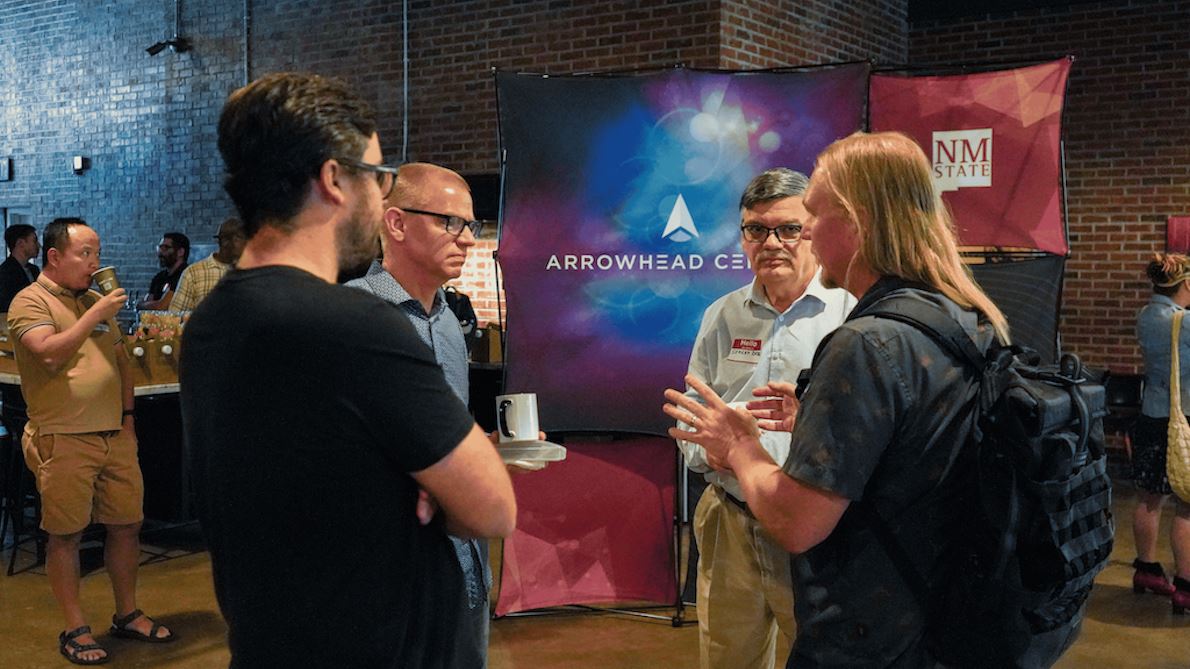 IMAGE DESCRIPTION Four people standing in an event area having a discussion