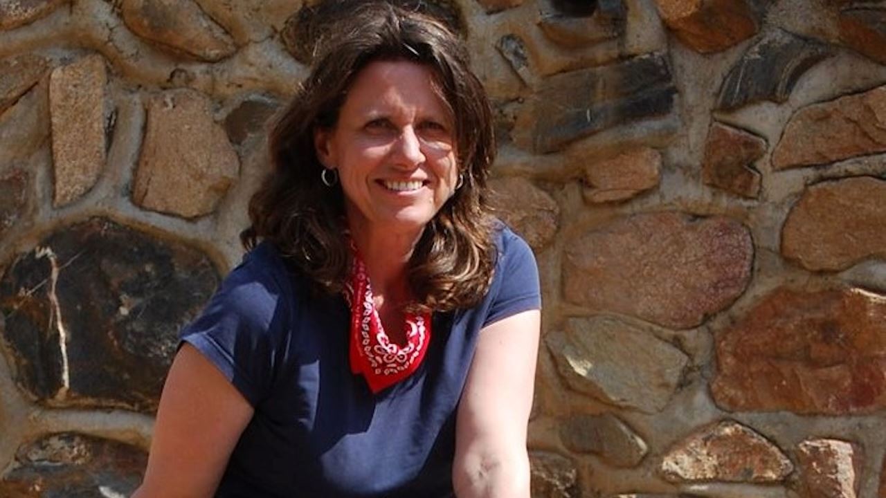 Woman sitting on a rock next to a stone fence