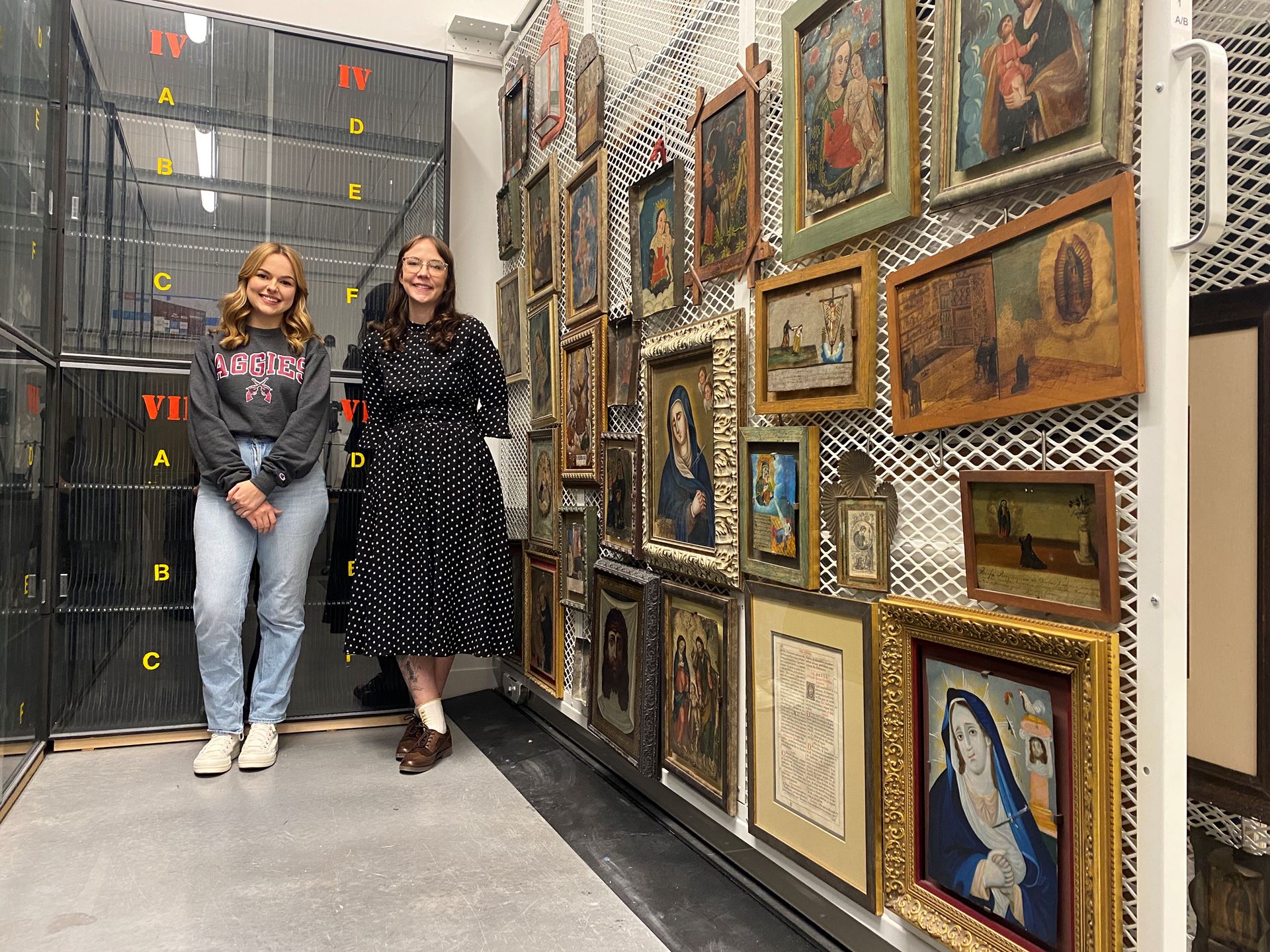 Two women standing next to painings