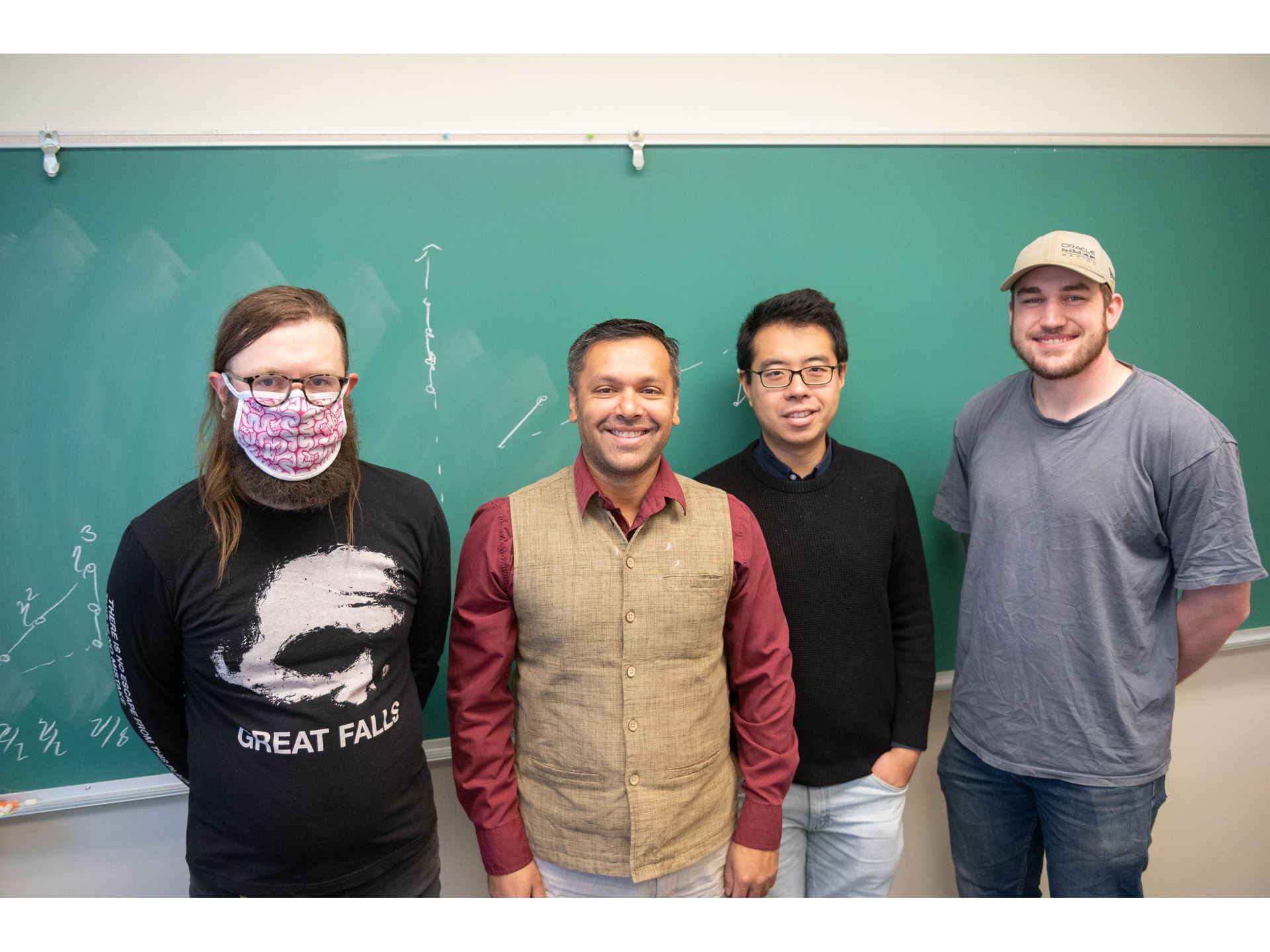 Four men in front of a chalkboard