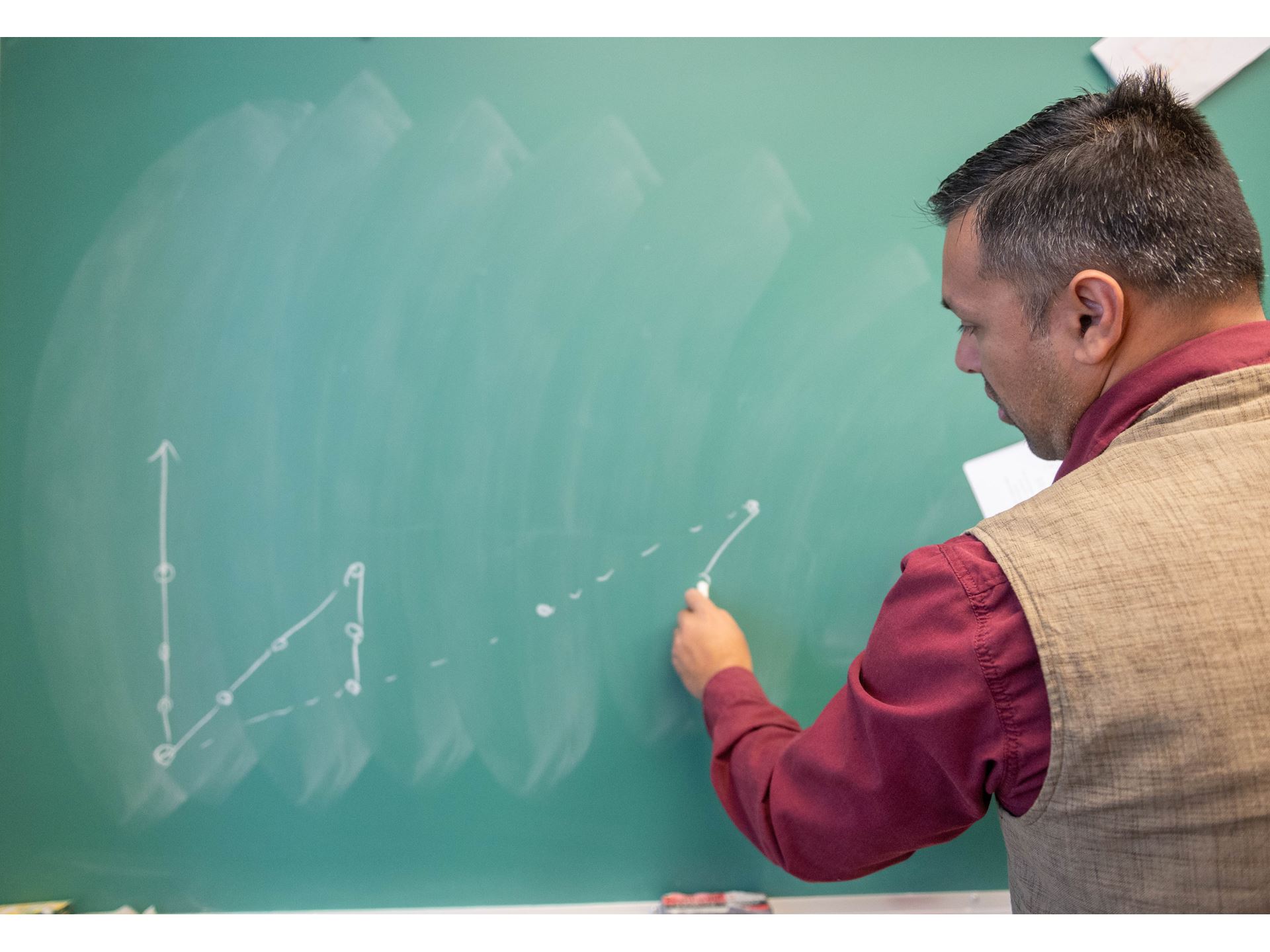 A man writing on a chalkboard