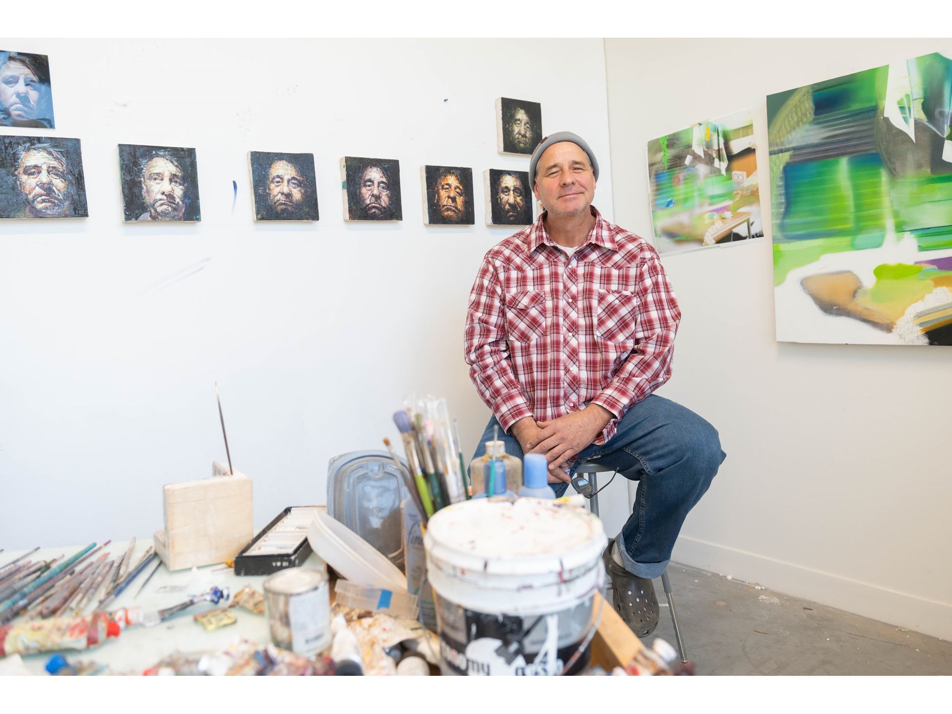 A man sitting in front of small paintings