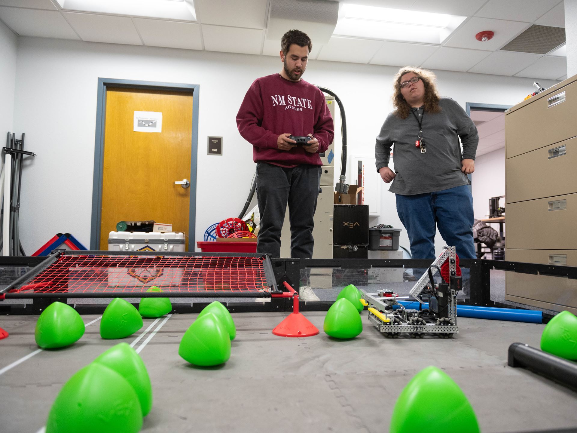 New Mexico State University Robotics members Mario Saenz, left, and Gene Fretwell work with a robot. The team hopes to one day host a national VEX U competition. (NMSU photo by Josh Bachman)