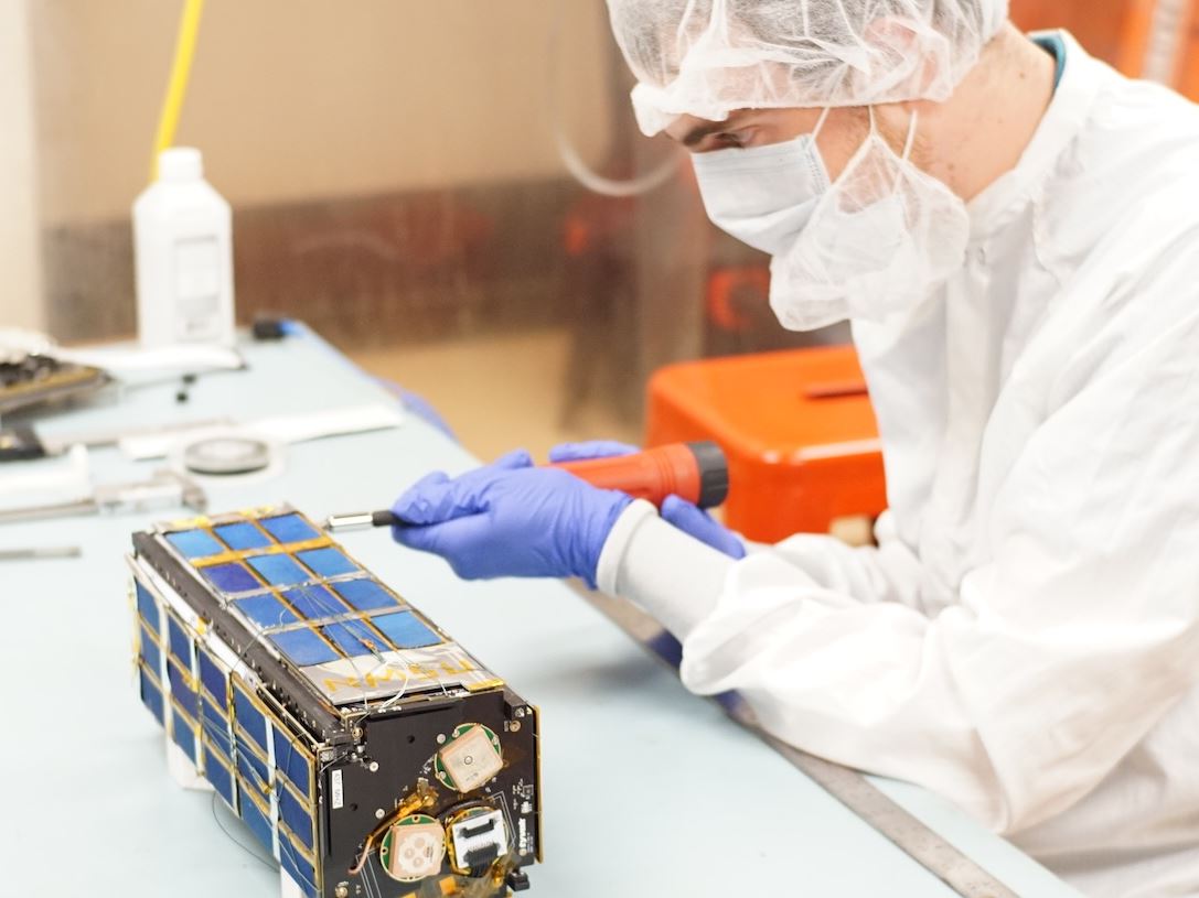 Description A student works on a nano satellite inside a cleanroom in the Klipsch School of Electrical and Computer Engineering