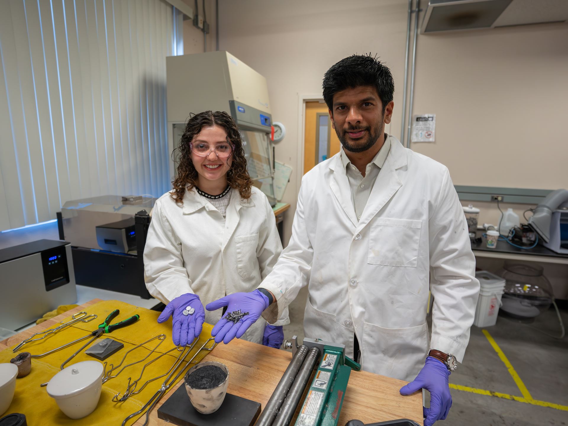 Description A professor and student hold scrap metal parts in a lab where they melt and reuse the metal