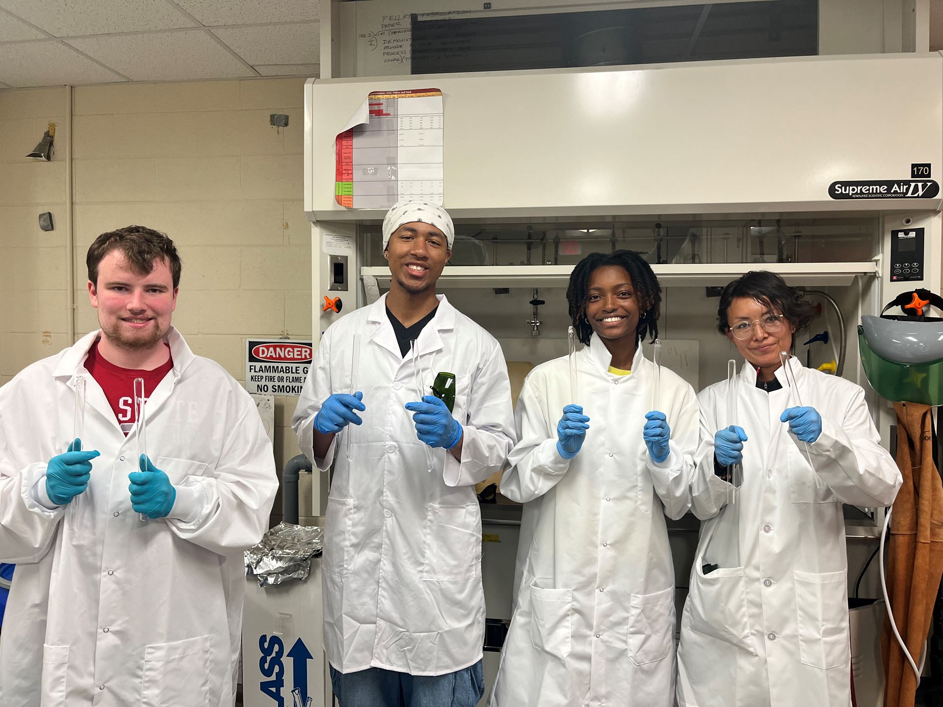 Description Four students attending New Mexico State University s NuChemE Pipeline summer initiative are holding up test tubes while in a lab