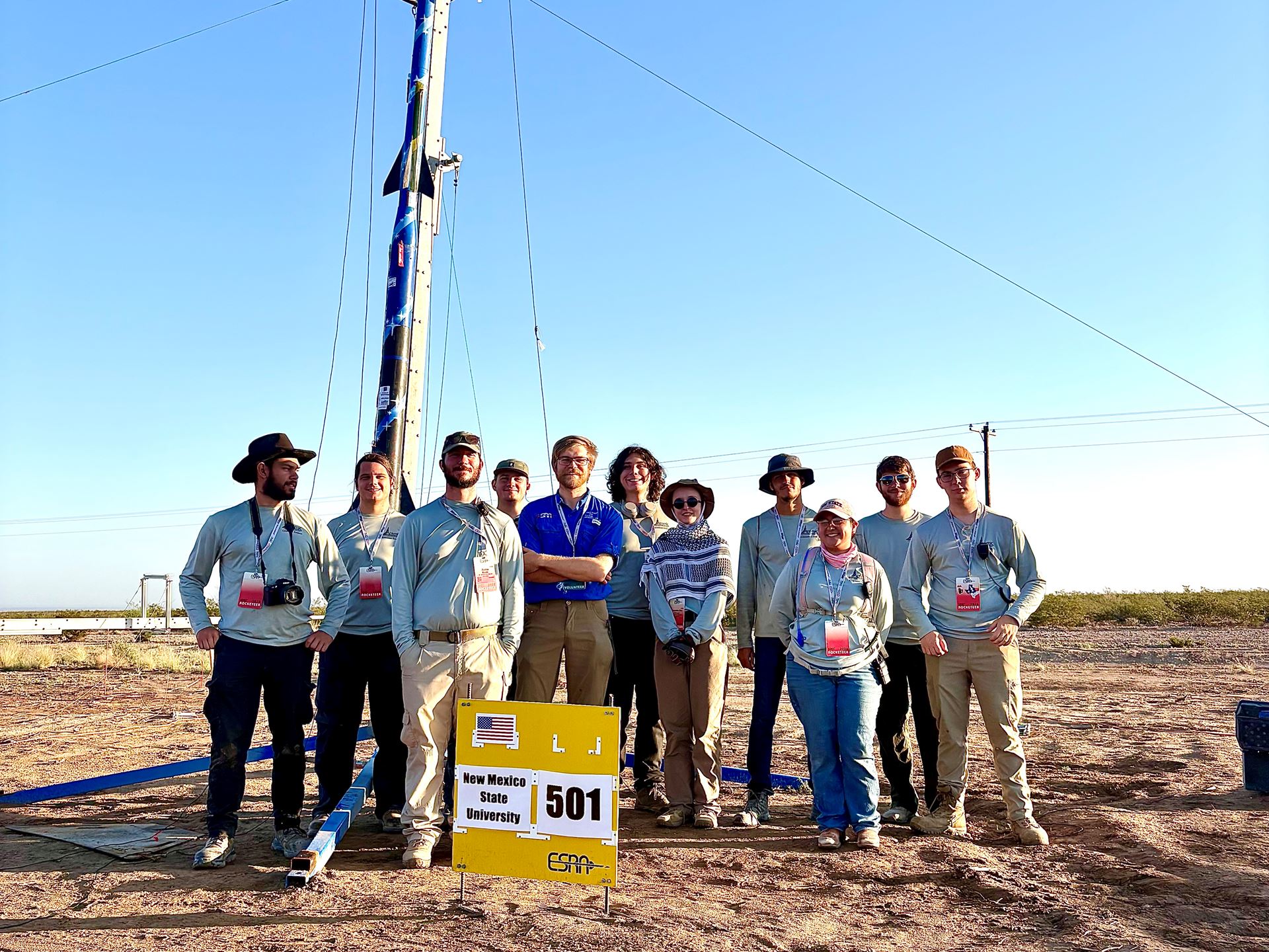 Description The team stands with their safety check lead in front of the rocket they built