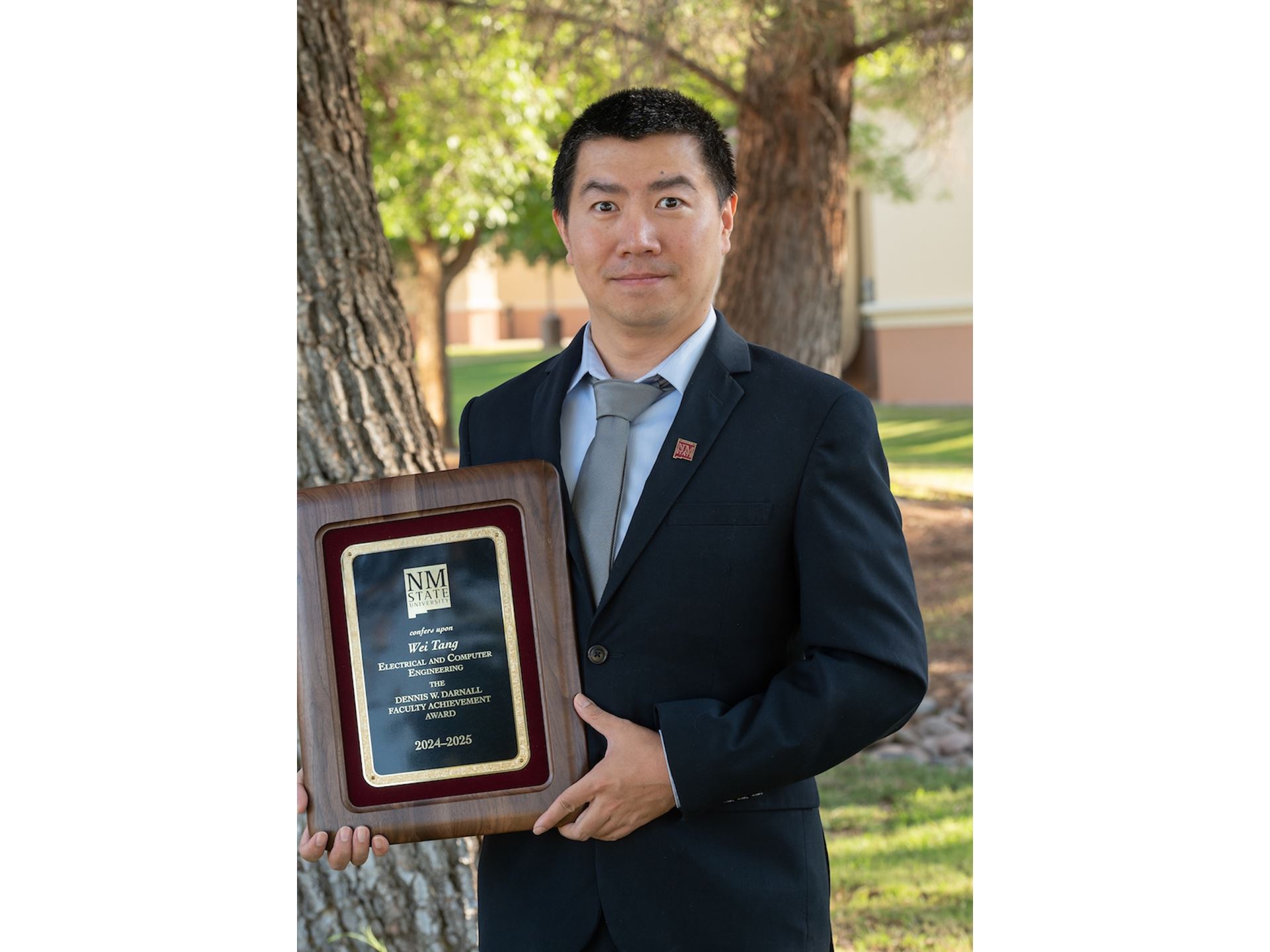 IMAGE DESCRIPTION Man standing outdoors holding a plaque