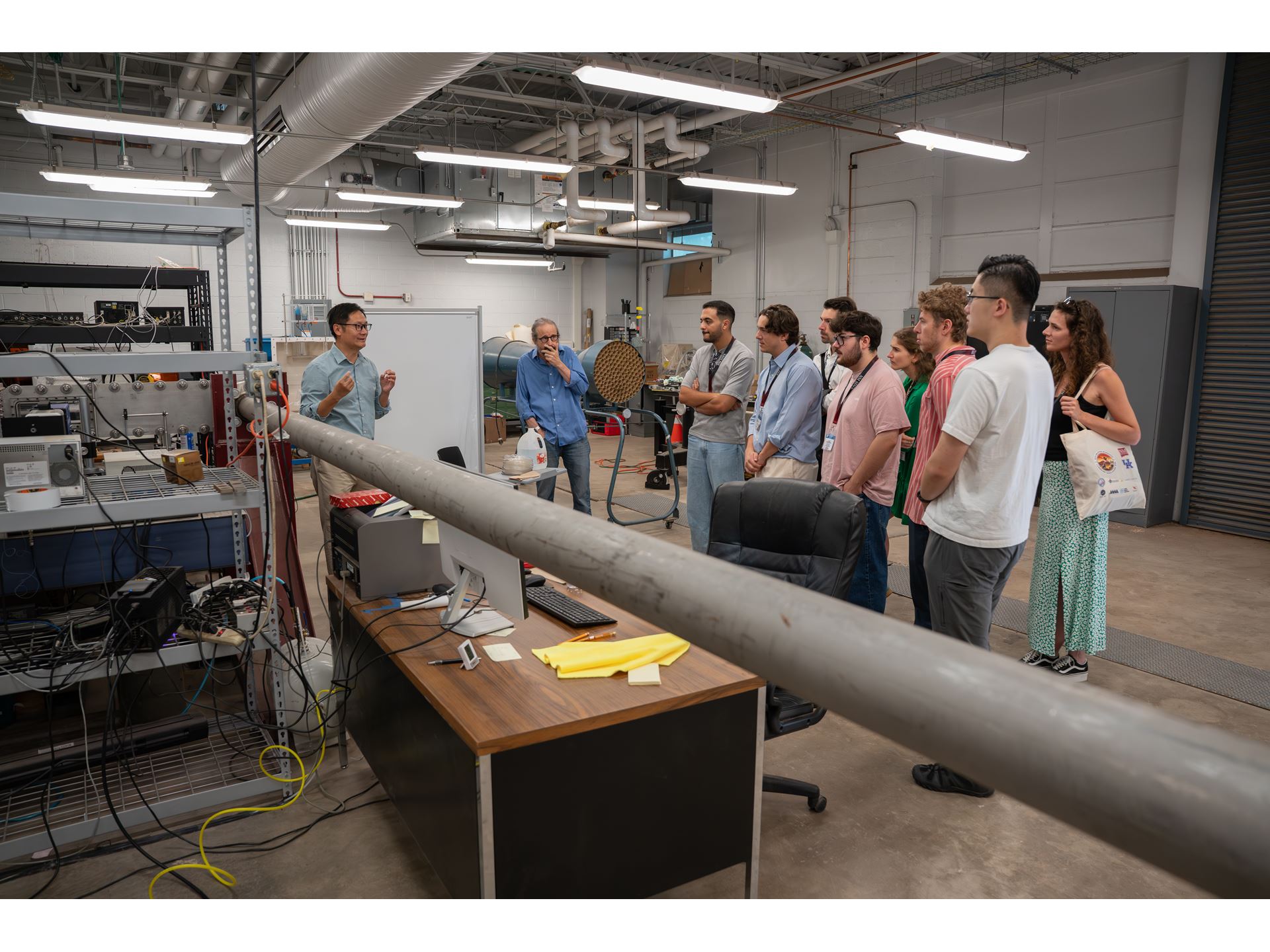Description A group of people listens to a speaker presenting in a laboratory