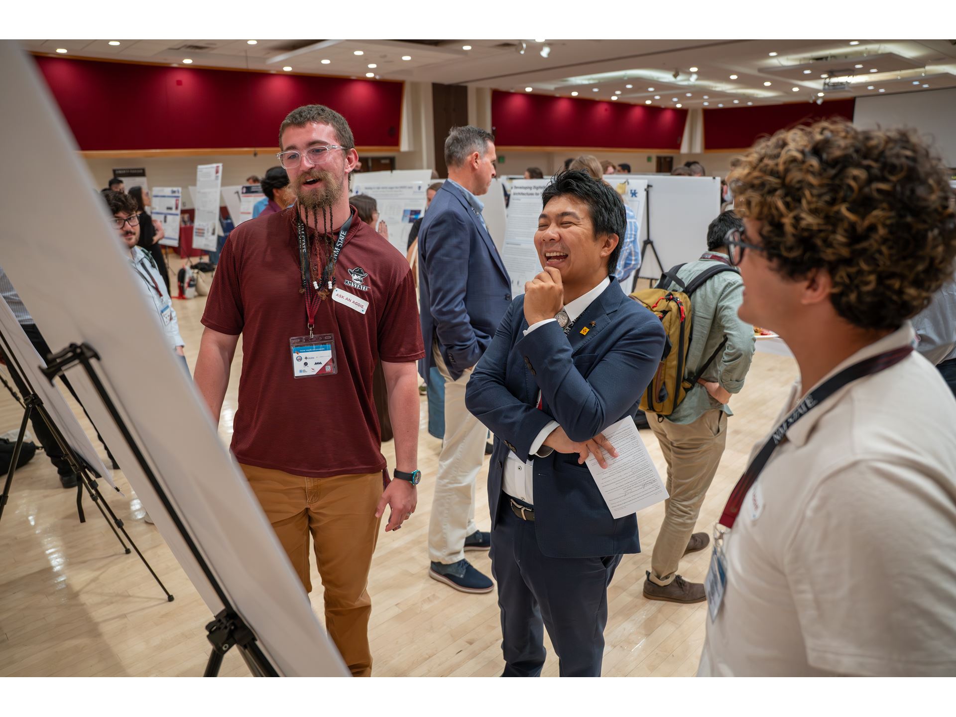 Description Three people stand in front of a research poster board smiling