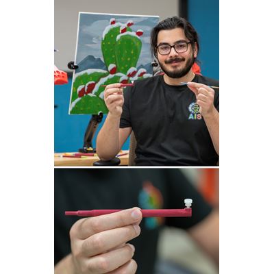 Above: Lead engineer Sami Naser holds the paintbrush sleeve and paintbrush in front of a painting done by Cueto.