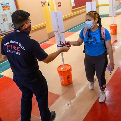 A firefighter with the New Mexico State University Fire Department distributes face masks to people on the NMSU campus i