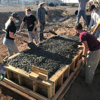 Students make finishing touches on fresh concrete in the bridge form. (Photo courtesy AWL)