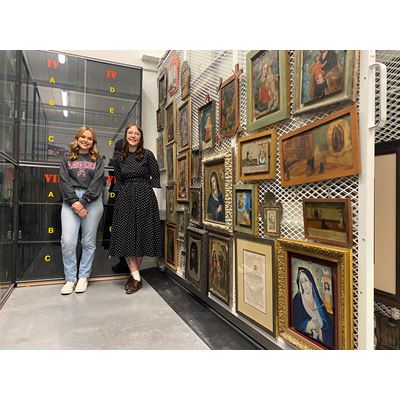 Two women standing next to painings