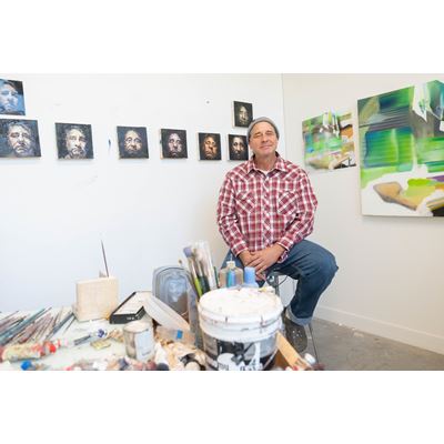 A man sitting in front of small paintings